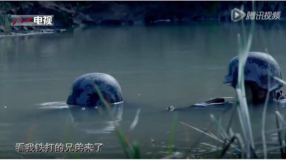 The helmets of two soldiers, poking out of a swamp