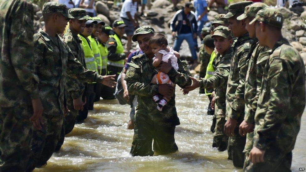 A soldier carries a baby over the Tachira river