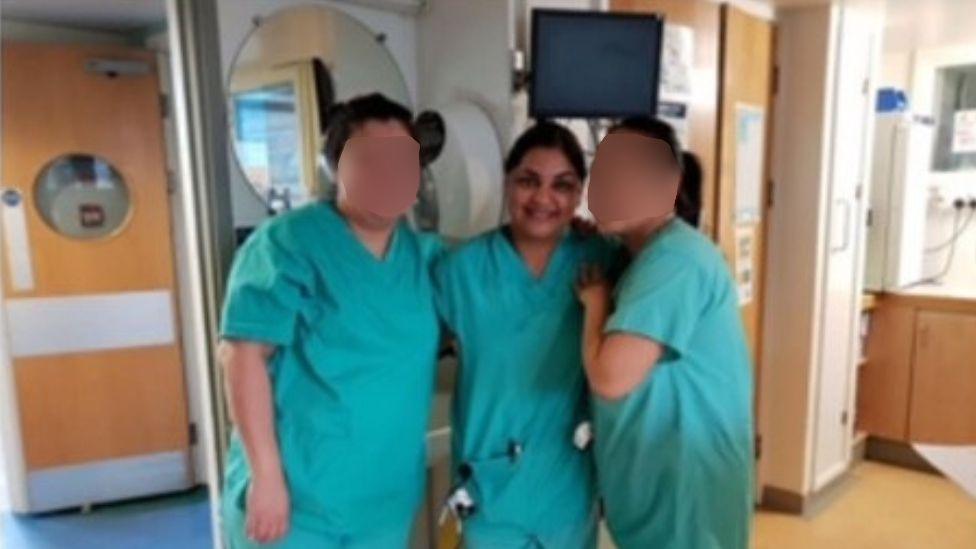 Tanya Nasir in her nurse uniform in a hospital ward, with her arms around two other nurses (faces blurred)