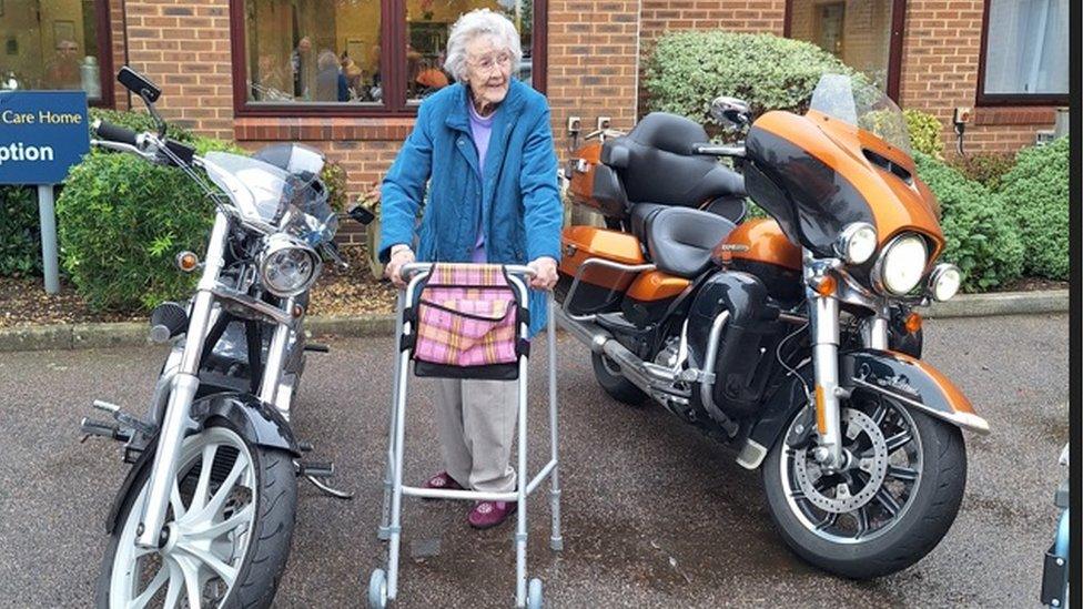 A resident with a walking frame stands between two large motorbikes