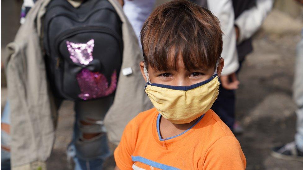 A child traveling with his parents wears his face mask at the entrance to Pamplona, Colombia