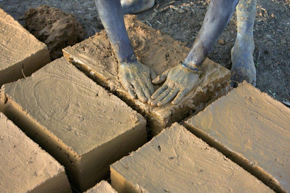 Evariste Citegetse shapes the mud bricks she will use to build her family's home in Ruyigi, Burundi