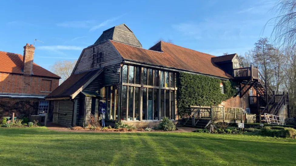 Modern barn looking building, with grass in front