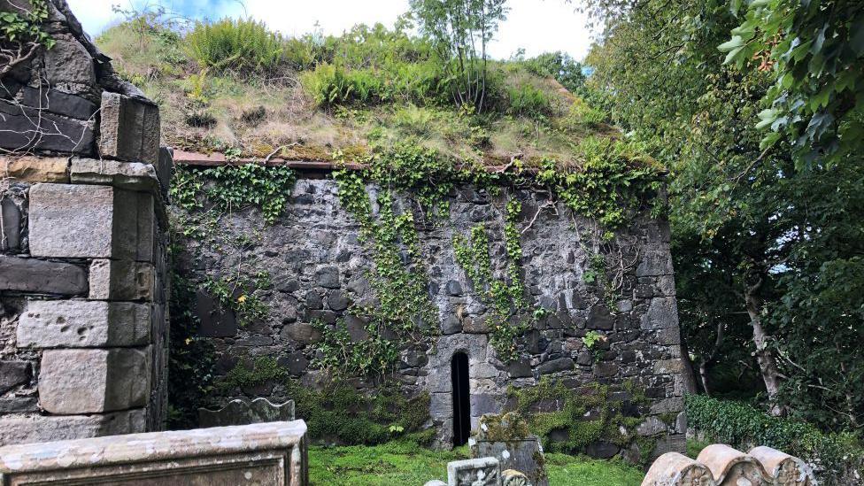 An old stone walled church with walls covered by ivy