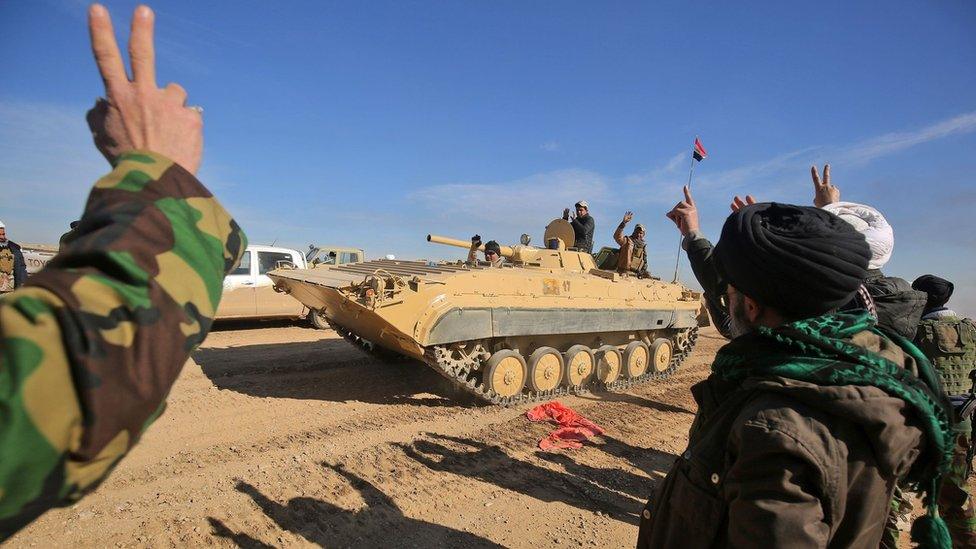Iraqi forces, supported by Popular Mobilisation militiamen, gesture as they advance south of Mosul on 20 February 2017