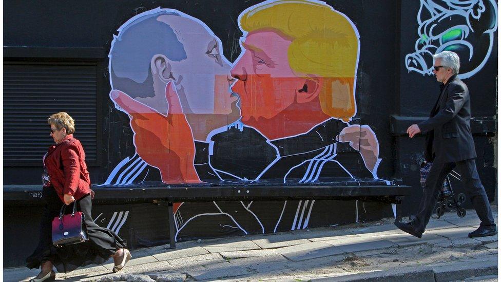 People walk past a mural on a restaurant wall depicting US Presidential hopeful Donald Trump and Russian President Vladimir Putin greeting each other with a kiss in the Lithuanian capital Vilnius on 13 May 2016.