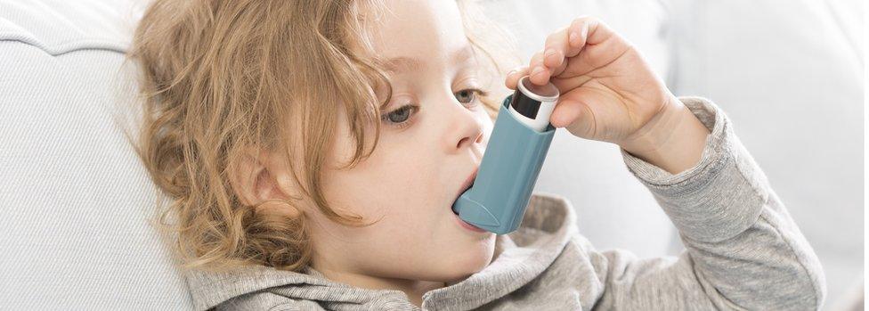 Small child using his inhaler device for asthma