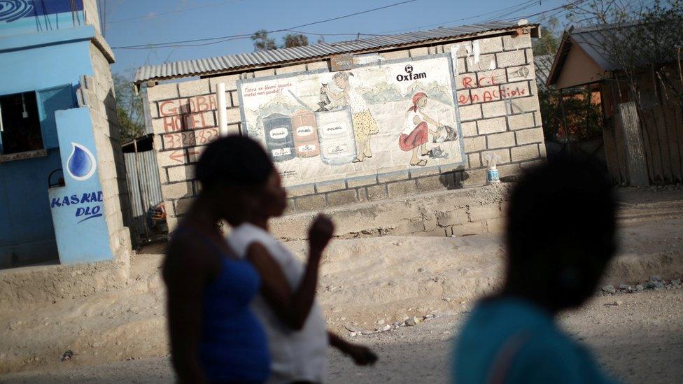 Women walk past an Oxfam sign in Corail, a camp for displaced people of the 2010 earthquake, on the outskirts of Port-au-Prince, Haiti, February 13, 2018.