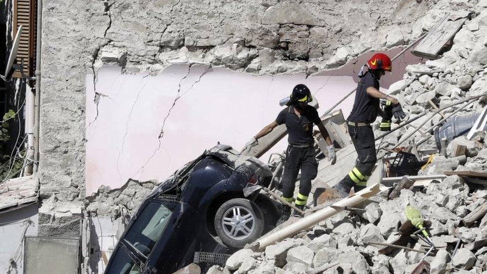 Rescuers make their way through destroyed houses in Pescara Del Tronto