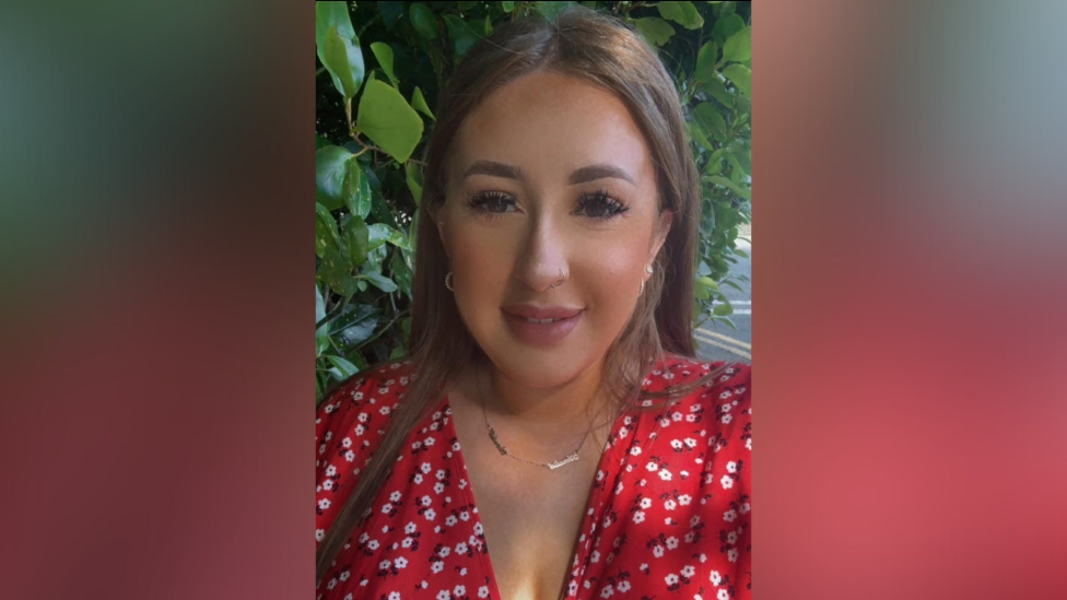 Sarah Montgomery. She has long brown hair and brown eyes, wearing a gold and earrings necklace and red floral top.