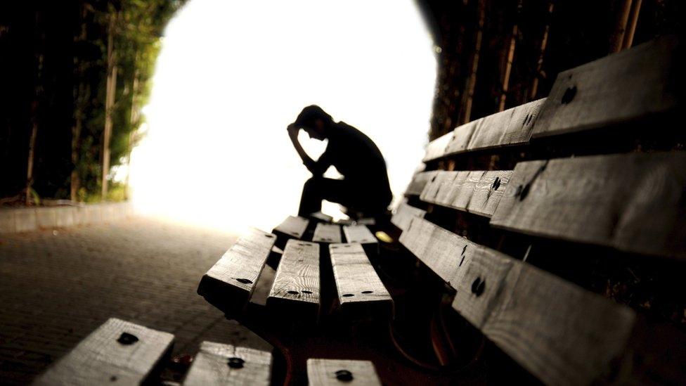 A man on a bench with his head in hands