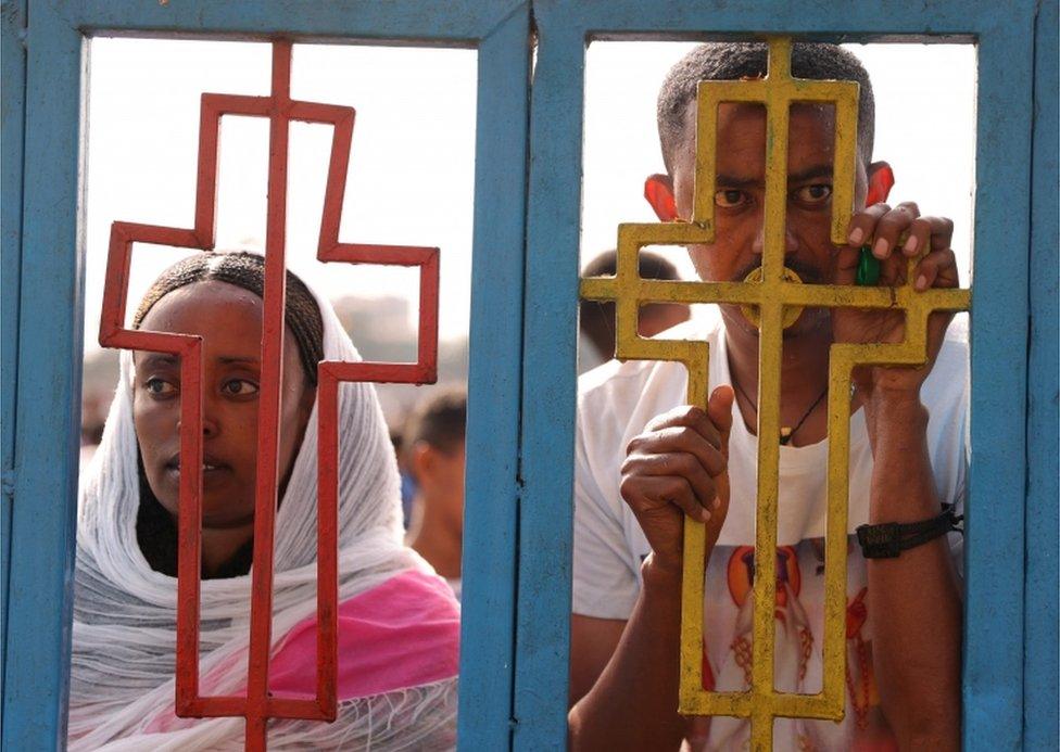 A man and a woman look through an iron gate.