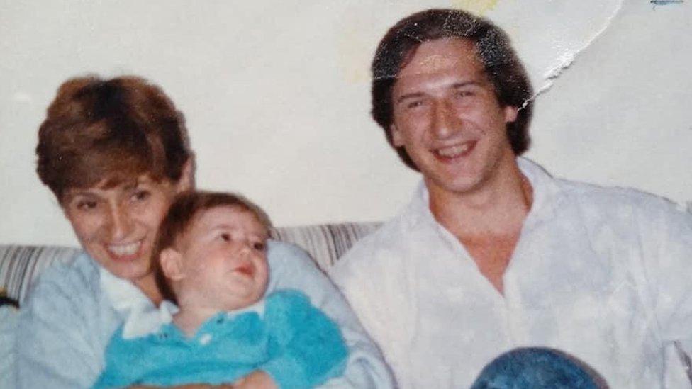 Ann Heron holding her Grandson while sitting beside Ralph Cockburn