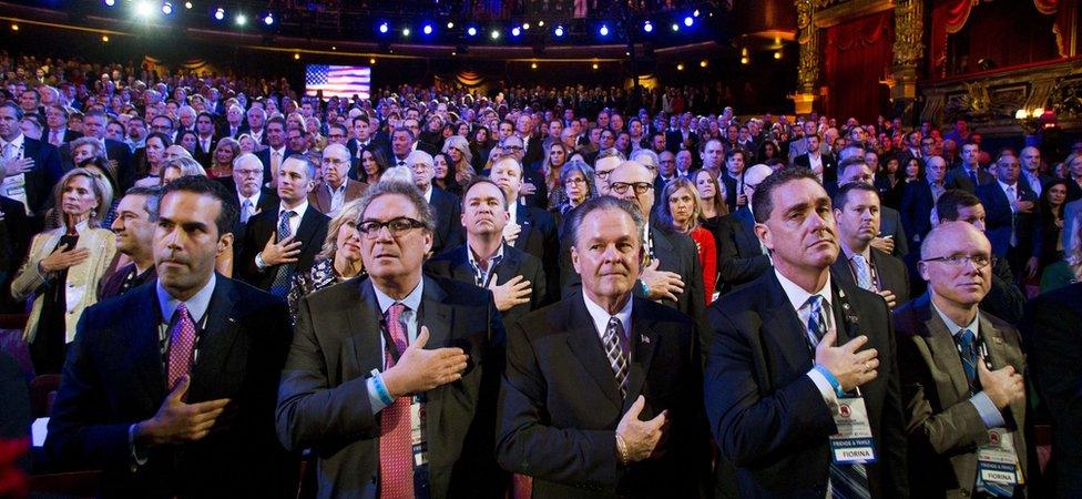 Members of the audience standing with their hands on their heart during a singing of the US National Anthem