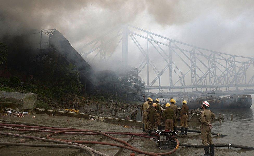 The Howrah bridge is pictured in the background as smoke rises from a burning godown in Kolkata on January 3, 2013.