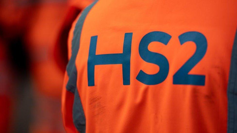 The orange fluorescent jacket of a worker at HS2's Curzon Street site in Birmingham. The characters HS2 appear in large print on the back.