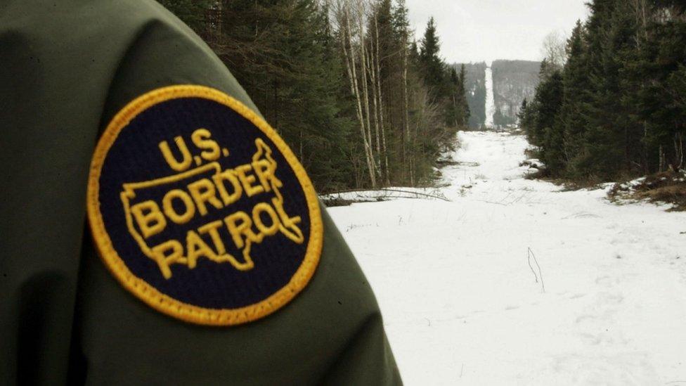 BEECHER FALLS, VT - MARCH 23: A U.S. Border Patrol agent stands along the boundary marker cut into the forest marking the line between Canadian territory on the right and the United States March 23, 2006 near Beecher Falls, Vermont. As American politicians continue to debate immigration reform, Border Patrol agents work the northern border to prevent illegal entry.