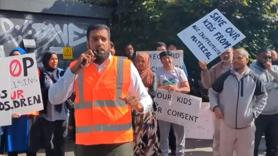 man speaks with microphone in front of rally