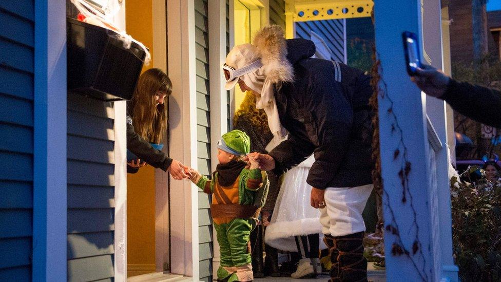 Mr Trudeau and his child at a door receiving candy