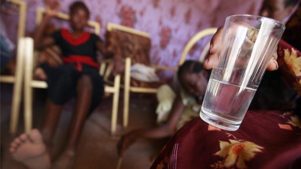 Sudanese Zakia (R), 23-years-old, who sells alcohol, holds a cup of her brew at her home in Halfaya near Khartoum on June 28, 2008.