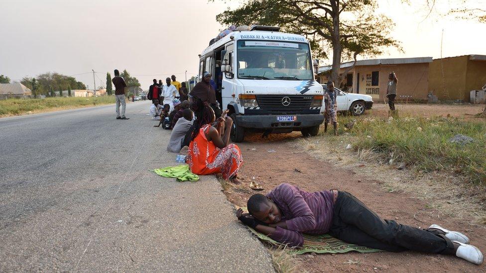 Passengers in Ivory Coast rest next to a bus, some 15km from Bouake which was rocked by a mutiny