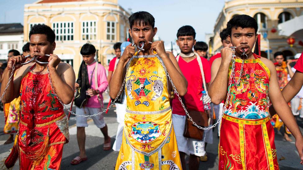 Devotees with piercing on their cheek are linked by a chain