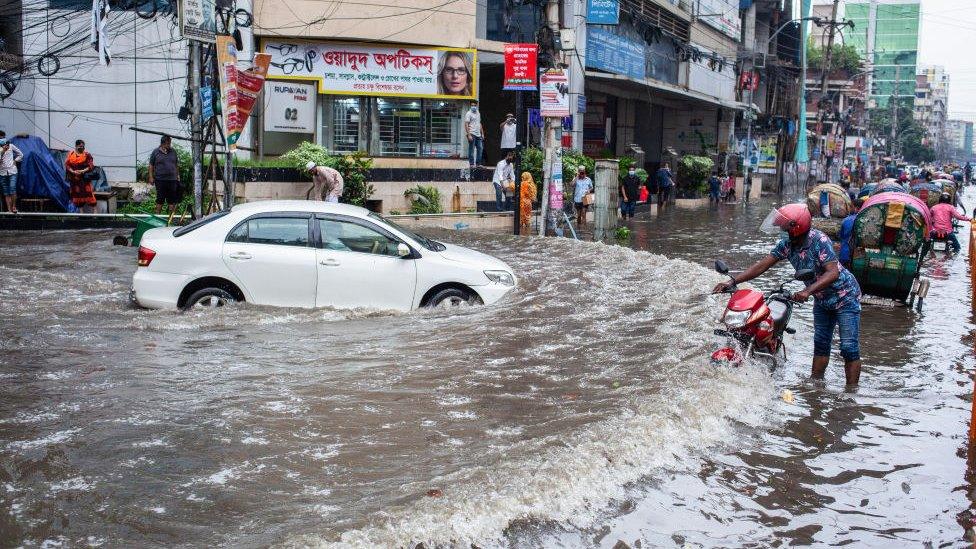 Car struggling through a flood in a Bangladesh