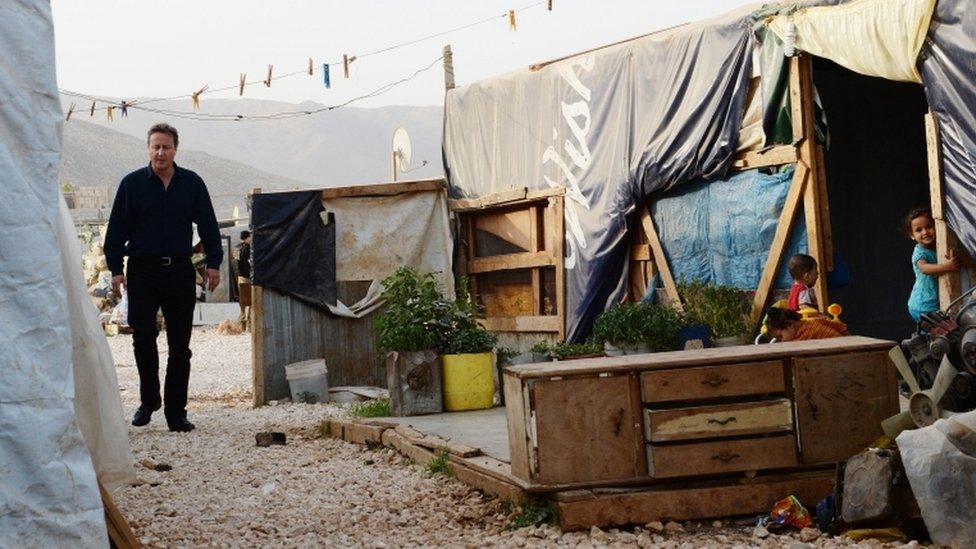 David Cameron walking through a camp housing Syrian refugee families