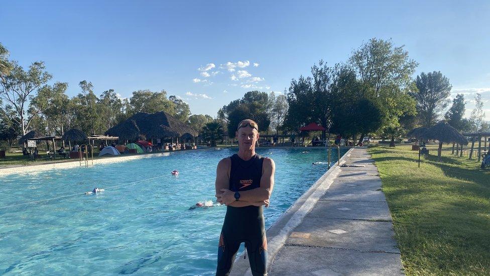 Stuart Gillett in front of a large outdoor swimming pool