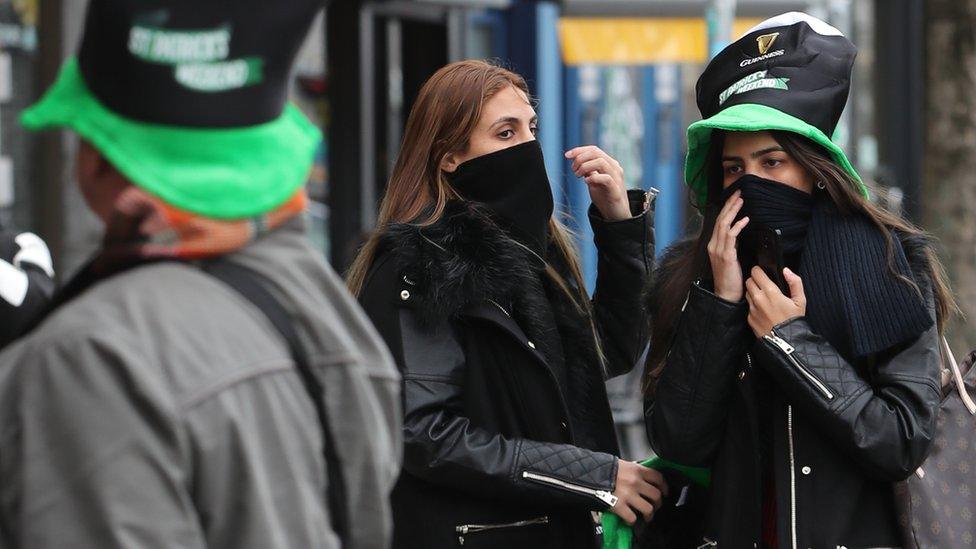 Tourists wearing scarves over their mouths near O'Connell Street in Dublin on St Patrick's day