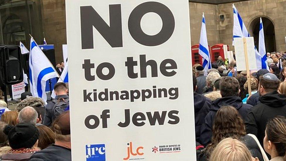 Crowds at a vigil with sign reading No to the kidnapping of Jews