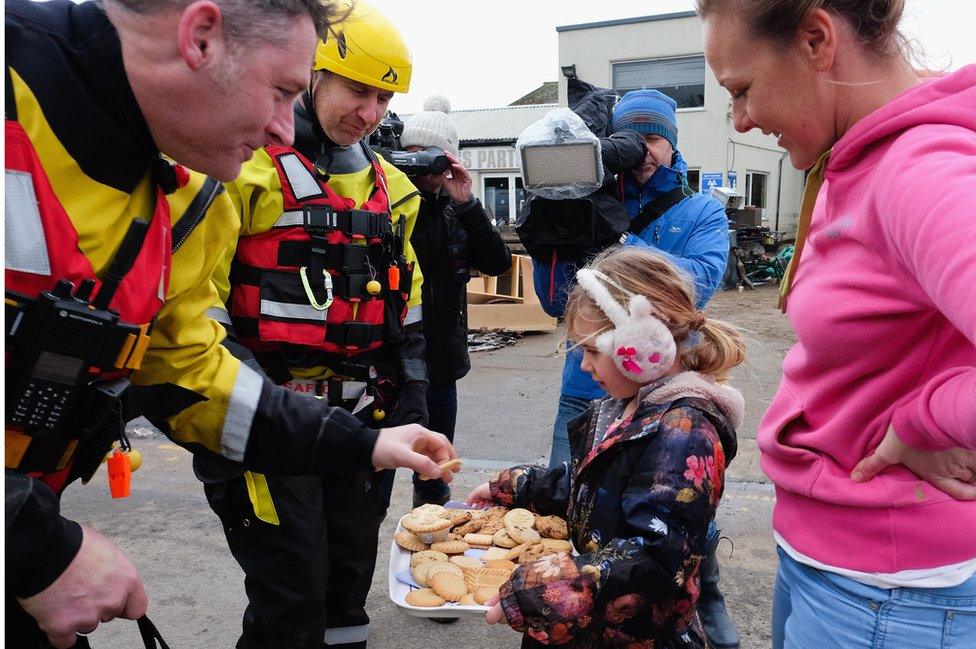 Isabelle Scott, 5, from Tadcaster hands out biscuits to emergency service personnel at the site of the collapsed bridge over the River Wharfe in Tadcaster