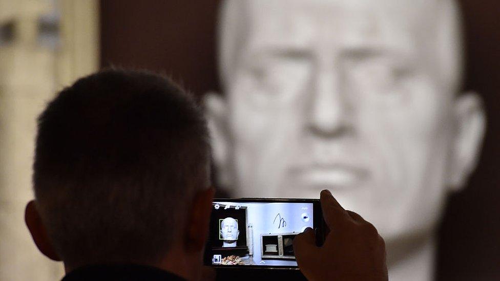 A man takes a picture of the tomb of Italian dictator Benito Mussolini