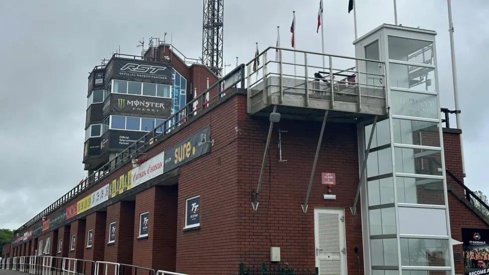 A close-up of the grandstand on an overcast day. The large red-brick structure has seating and a viewing tower for race controllers.