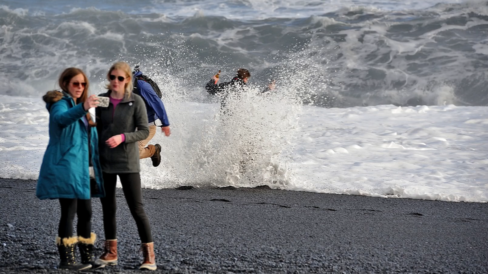 Tourists being struck by waves on the beach at Reynisfjara