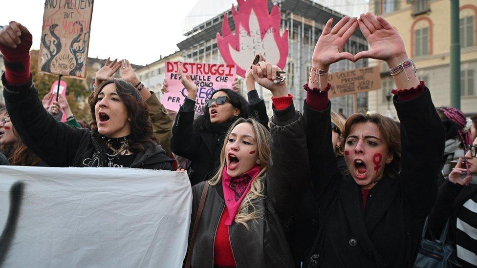 Women with their arms raised in the air protesting in Italy