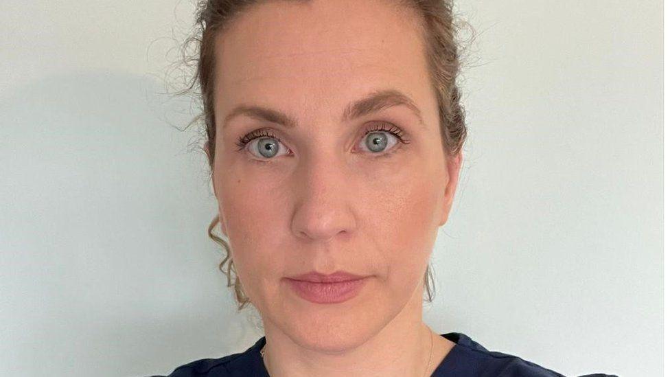Dr Fiona Hunter had tied back brown hair and looks at the camera. She wears a dark top.