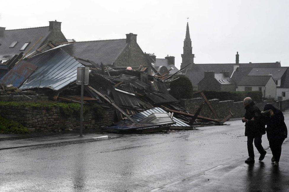 Pedestrians walk past a destroyed warehouse in Porspoder, western France, on November 2, 2023