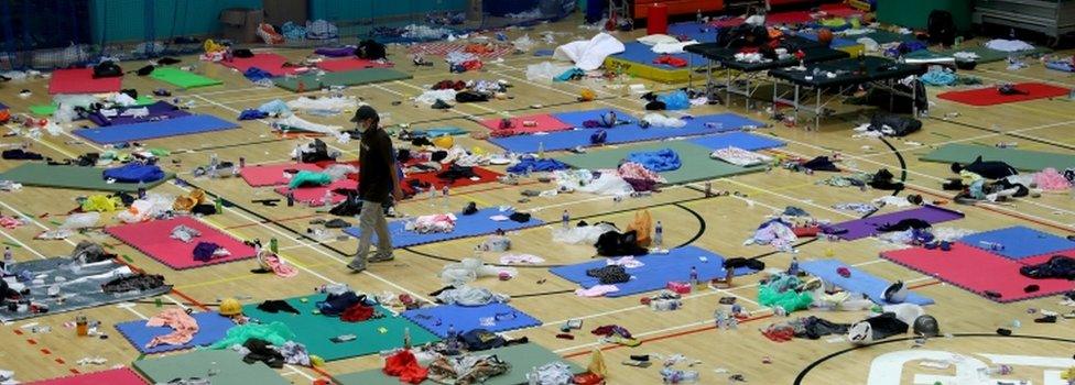 A protester walks between mats on the floor of PolyU gymnasium