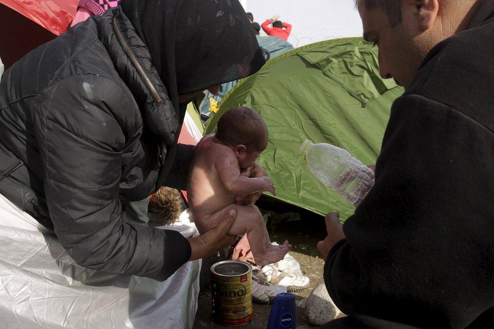 A migrant couple wash their newborn baby near Idomeni, Greece, 6 March