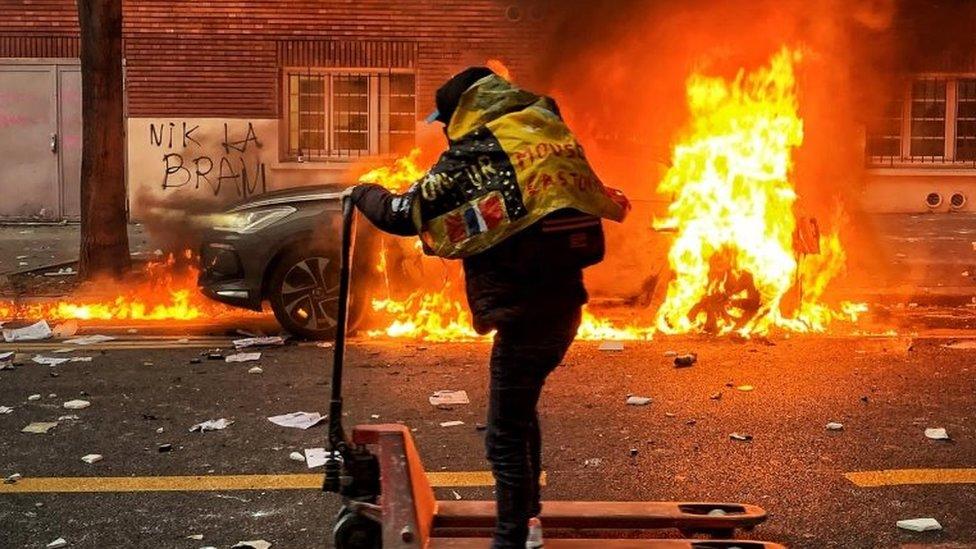 A protester moves on a hand lift truck as a car is on fire during a protest against France"s controversial global security law, in a street between Porte des Lilas and Gambetta square, in Paris, France, 05 December 2020