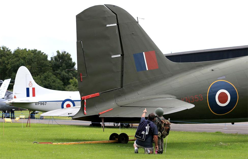 Visitors look at a vintage war plane in an outdoor museum