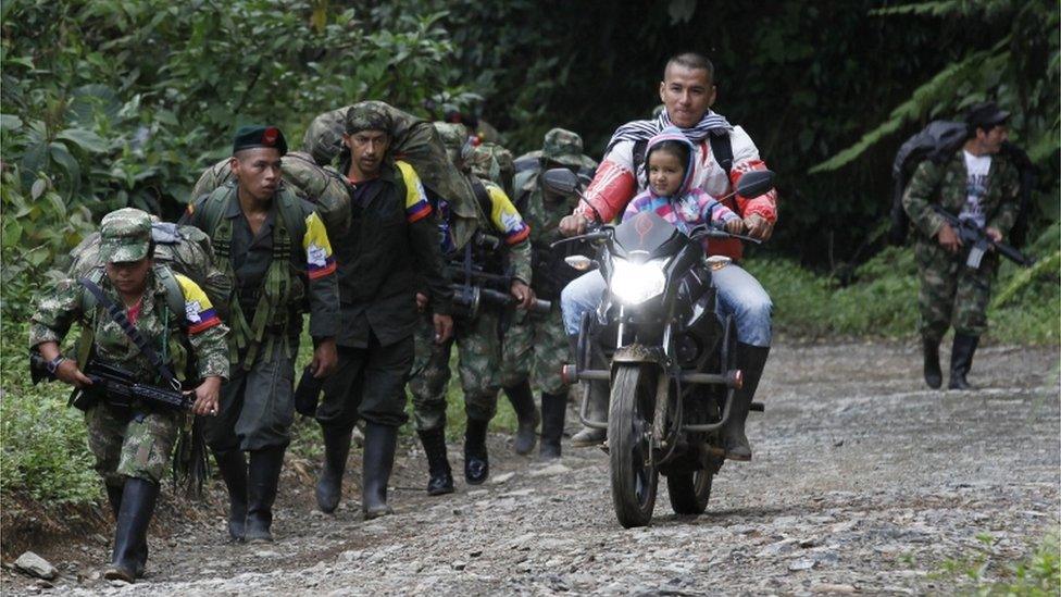 Farc rebels march towards a transition zone as a local resident rides past with a child on a motorbike in Cauca province, in Colombia, on 31 January 2017