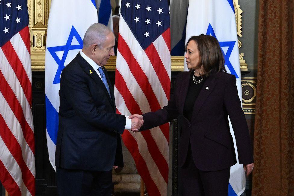 Netanyahu and Harris shake hands in front of their national flags