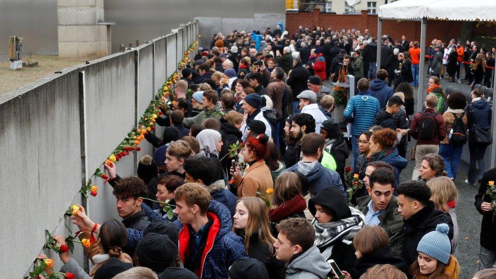 People place roses at the Wall memorial during a ceremony marking the 30th anniversary of the fall of the Berlin Wall at Bernauer Strasse in Berlin, Germany - November 9, 2019