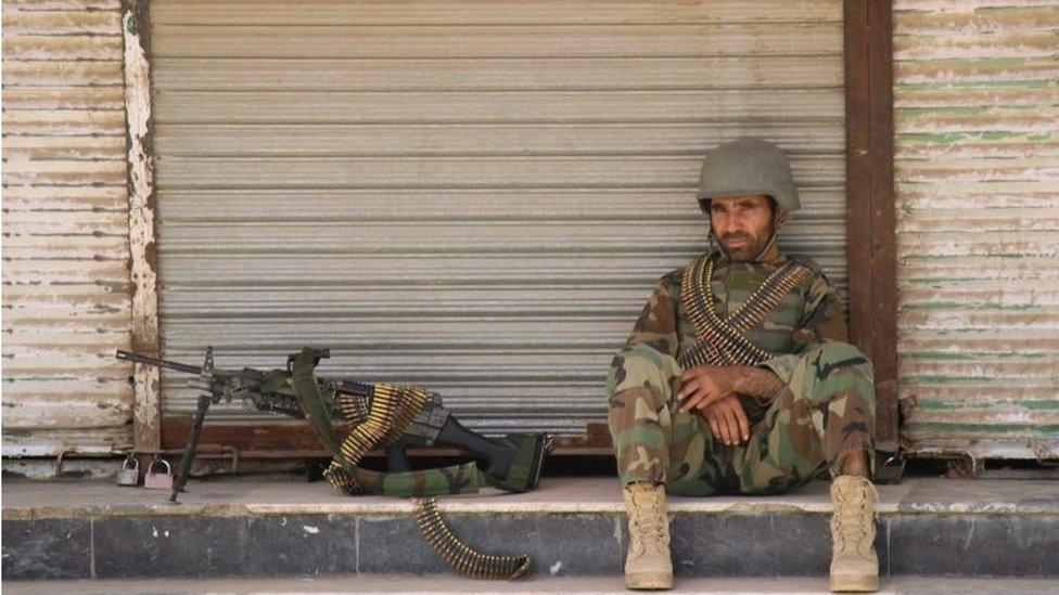 An Afghan National Army (ANA) soldier sits in front of a closed shop in the downtown of Kunduz city, Afghanistan October 3, 2016.