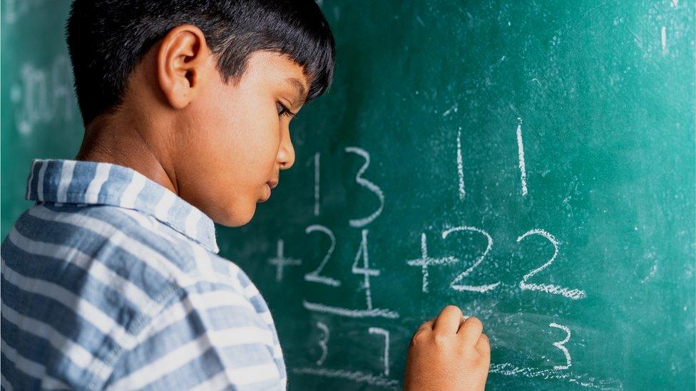 boy writing sums on blackboard