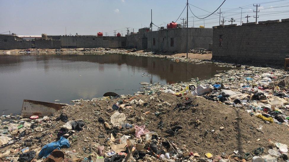 A reservoir of dirty water surrounded by litter