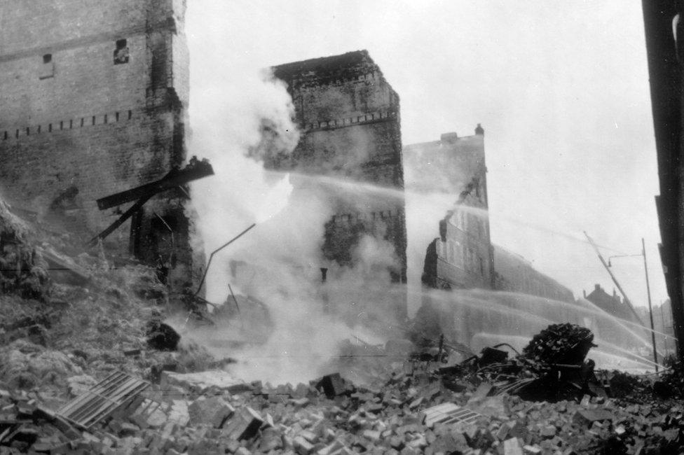 Hoses being played on to the still burning whisky warehouse in Glasgow's dockland. The warehouse, containing thousands of gallons of whisky caught fire last night, and 14 firemen and six salvage men lost their lives in fighting the blaze. It is estimated the damage amounts to £10m.