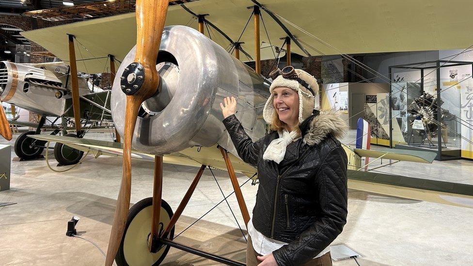 An actress dressed as Amelia Earhart poses in front of a propeller plane at Aerospace Bristol